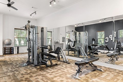 A gym with a variety of equipment including a leg press machine, a bench press, and a squat rack.