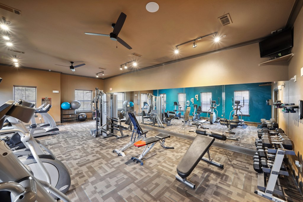 a gym with cardio equipment and weights on a tiled floor
