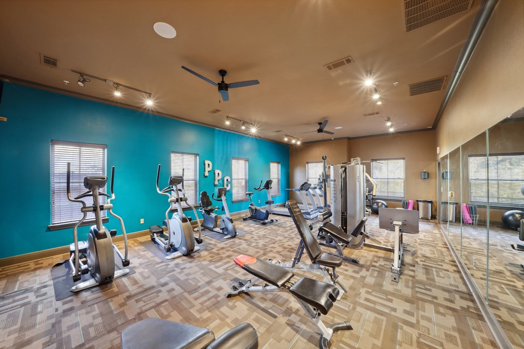 a gym with cardio machines and weights on a wooden floor