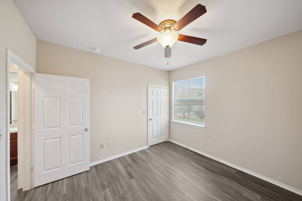 an empty bedroom with a ceiling fan and a window