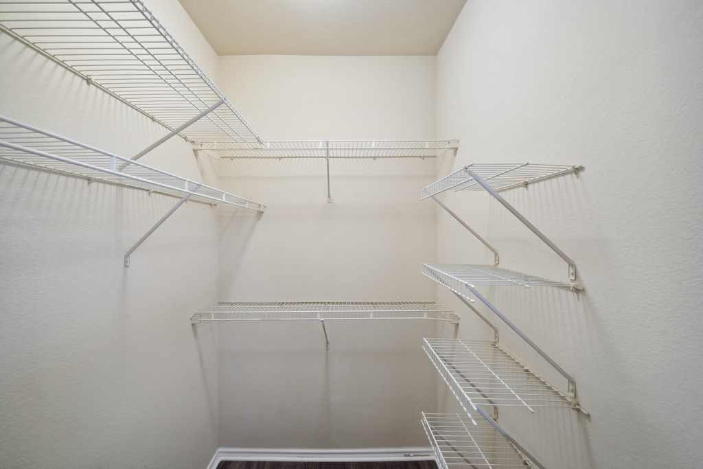 a walk in closet with white walls and metal stairs