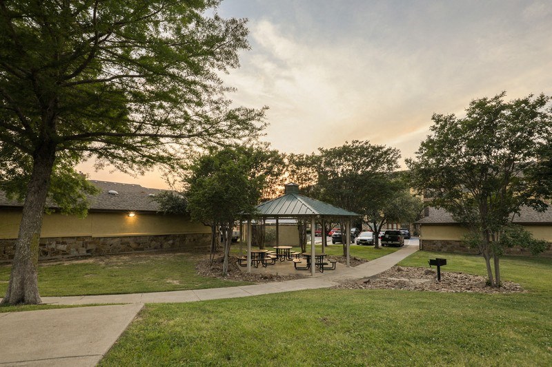 a gazebo in a park next to a sidewalk