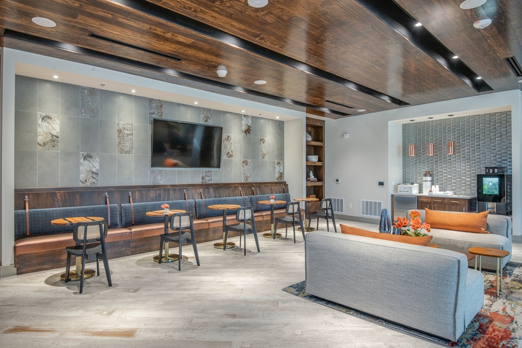 the lobby of a hotel with tables and chairs and a tv