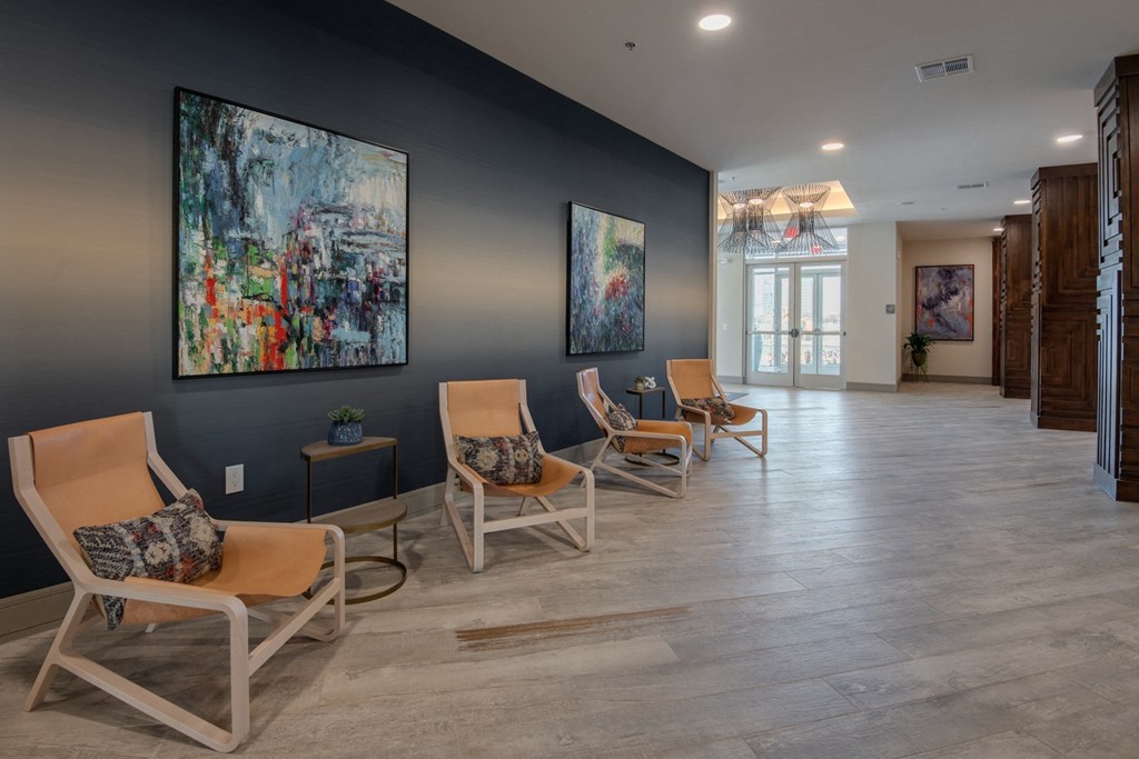 a row of rocking chairs in a lobby with paintings on the wall