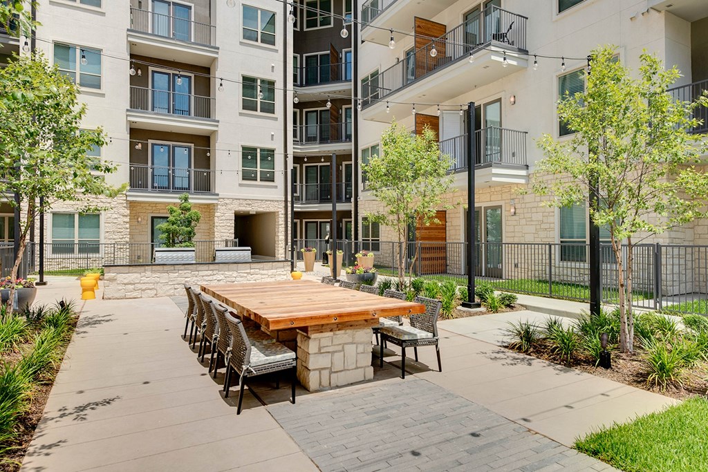 an outdoor dining area with a table and chairs in front of an apartment building