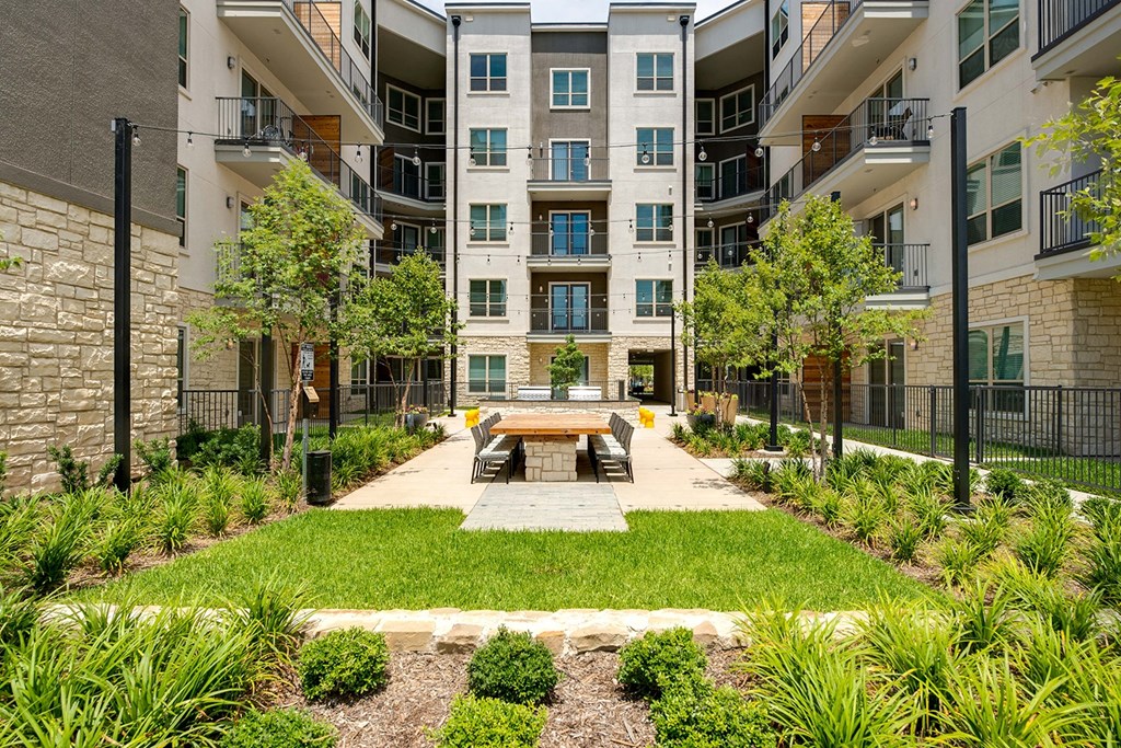 an outdoor courtyard with a picnic table in front of an apartment building