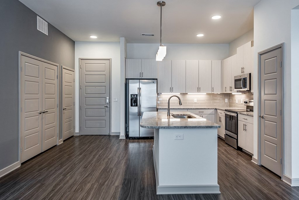 an empty kitchen with white cabinets and a marble counter top