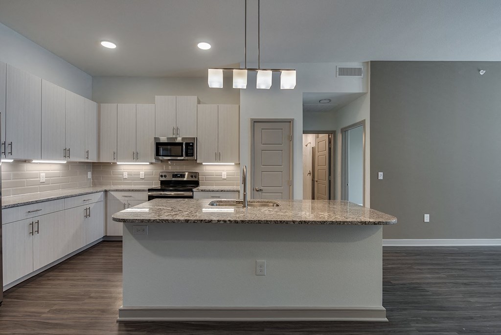 an empty kitchen with white cabinets and a granite counter top