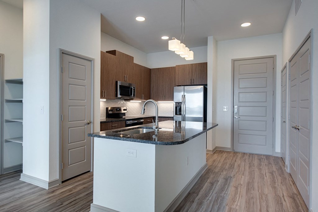 a kitchen with an island and a stainless steel refrigerator