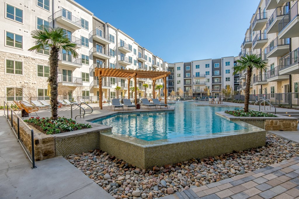 a swimming pool with palm trees in front of an apartment building
