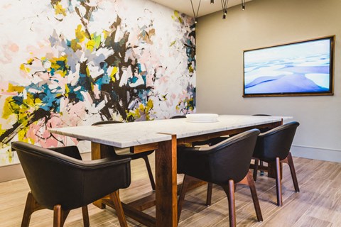 a dining room with a table and chairs and a painting on the wall