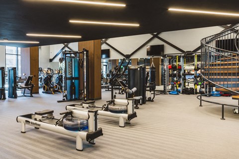 a gym with weights and cardio equipment and a staircase