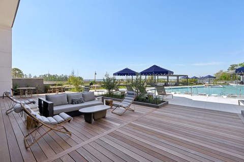 A wooden deck with a couch and chairs overlooking a pool.