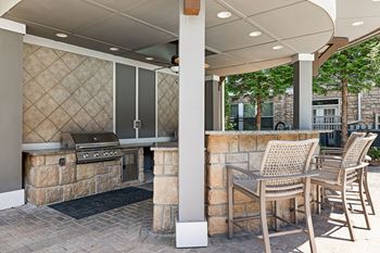 A patio with a grill and chairs.