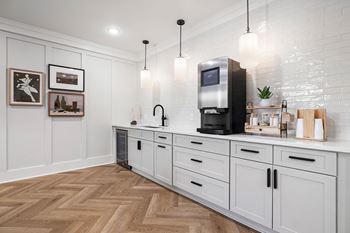 A kitchen with a white brick wall and wooden floors.