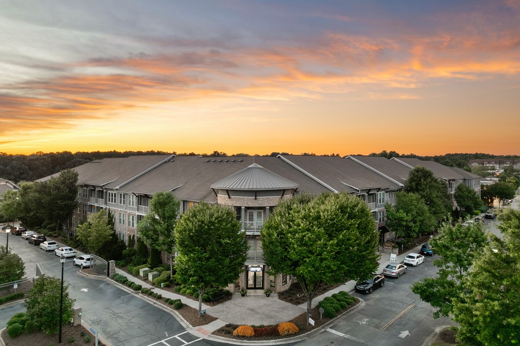 A sunset view of a residential area with apartment buildings and parked cars.