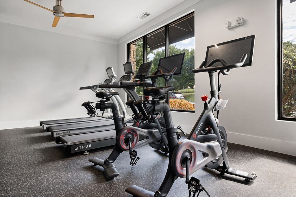 A room with a treadmill, a stationary bike, and a fan.