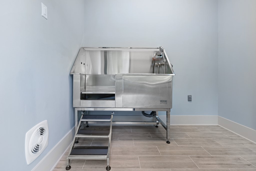 A large stainless steel table with a white cloth on it is in a room with light blue walls.