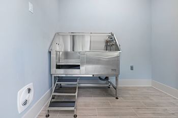 A large stainless steel table with a white cloth on it is in a room with light blue walls.