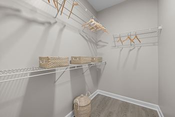 A white closet with clothes hangers and baskets on shelves.