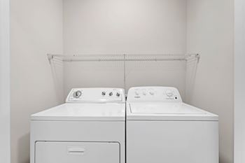 Two white washing machines in a white room.