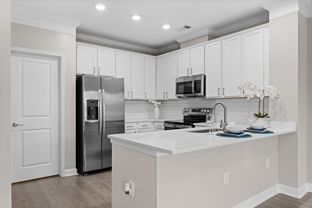 A kitchen with white cabinets and a white island.