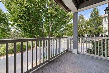 A balcony with a railing and a view of trees and a road.