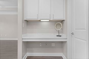 A white cabinet with a light on top and a wreath hanging on the wall.