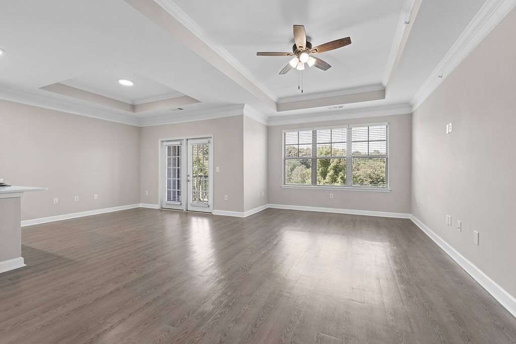 A spacious room with a ceiling fan and sliding glass doors leading to a balcony.