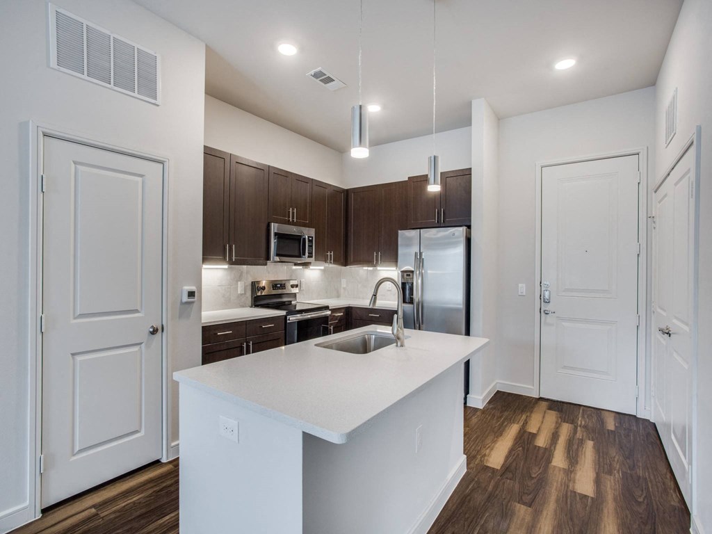 a kitchen with a large island and a stainless steel refrigerator