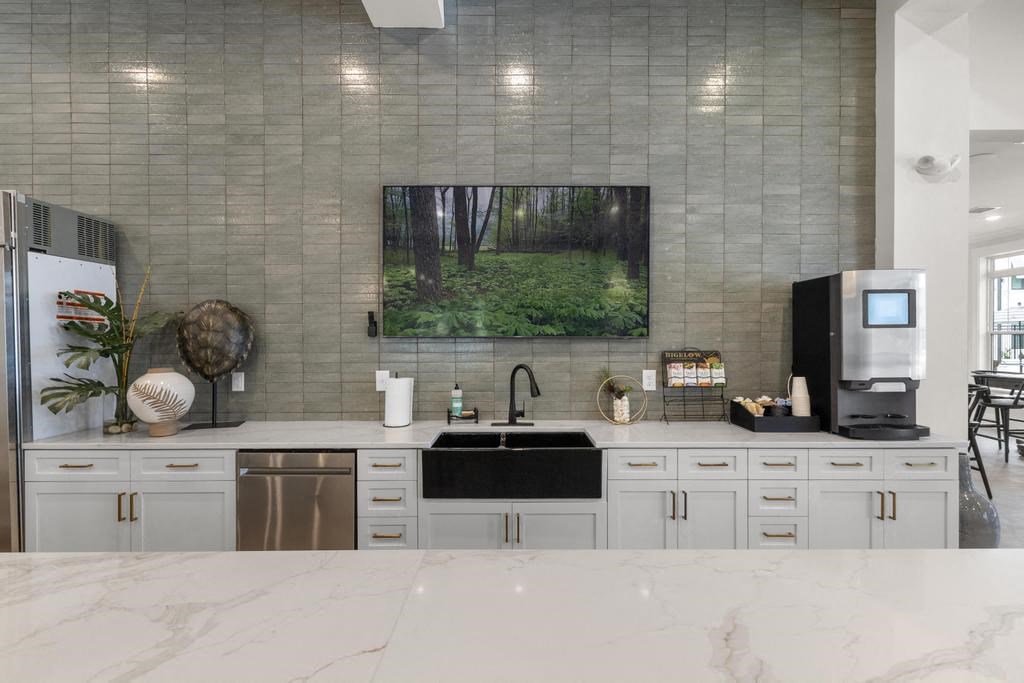 a white kitchen with a sink and a tv on the wall