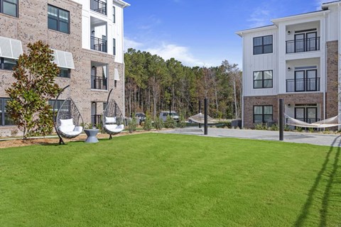 a large lawn with hammocks in front of an apartment building