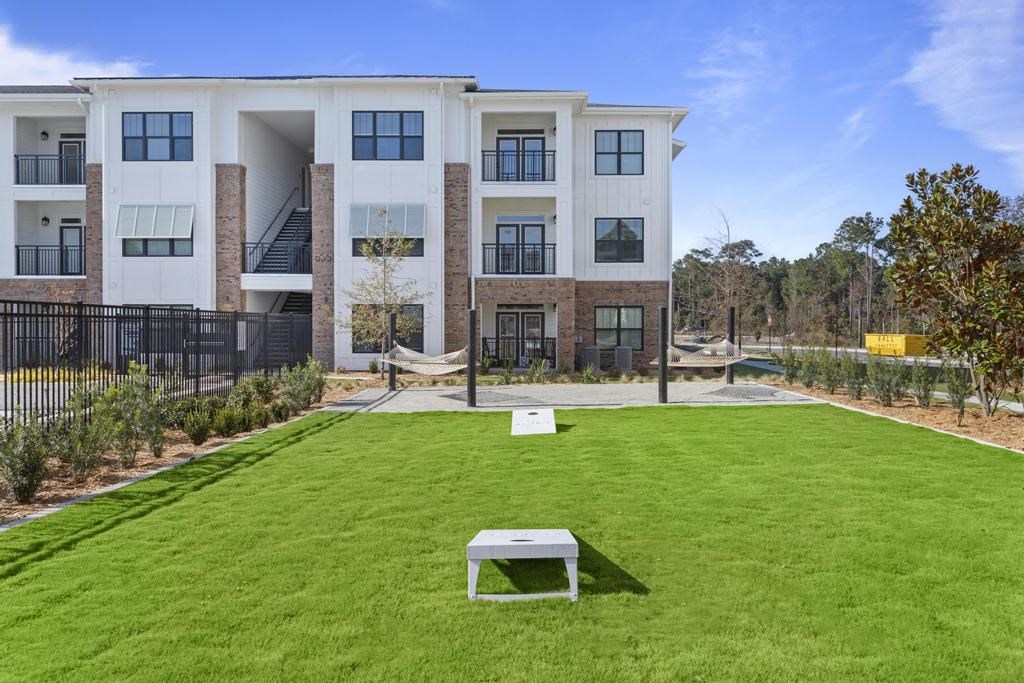 an apartment building with a lawn and a picnic table in front of it