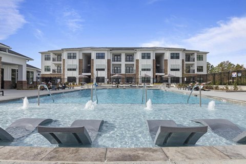 a large swimming pool with chairs in front of a building