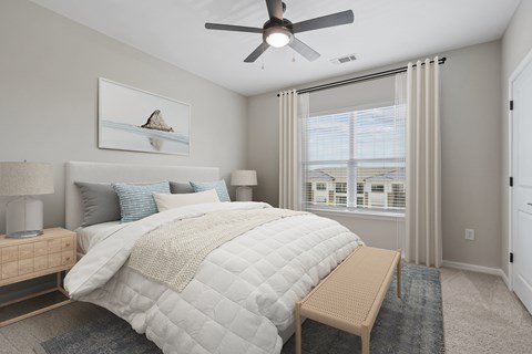A bedroom with a large bed, a ceiling fan, and a window with blinds.