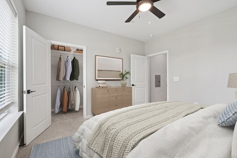 A bedroom with a bed, dresser, mirror, and closet.