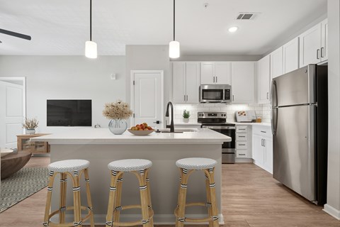A modern kitchen with a white island and bar stools.