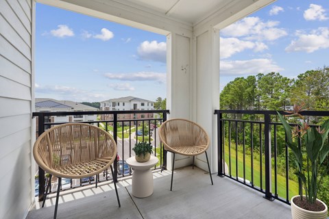 Two chairs on a balcony overlooking a green landscape.