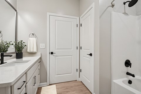 A white bathroom with a sink, mirror, and bathtub.