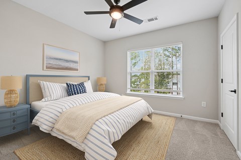 A bedroom with a bed, nightstand, and window.