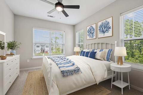 A bedroom with a large bed, a ceiling fan, and a window with blinds.