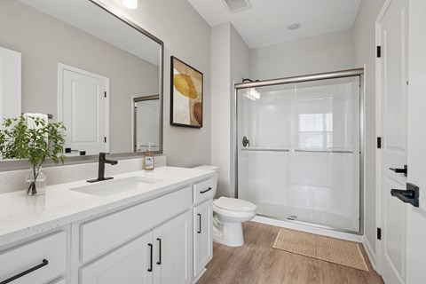 A bathroom with a toilet, sink, and shower.