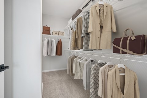 A white closet with a variety of coats and bags.