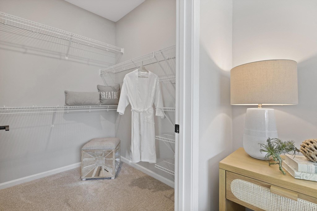 a closet in a bedroom with a white robe and a nightstand