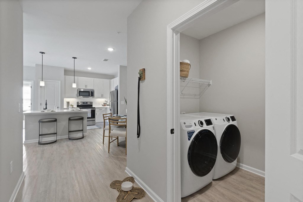 a washer and dryer in a laundry room with a kitchen in the background