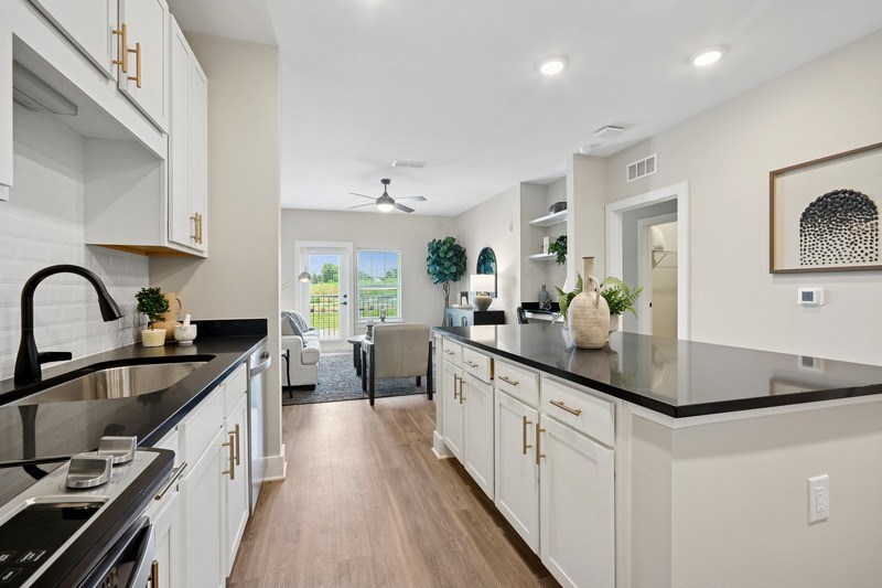 A modern kitchen with white cabinets and black countertops.