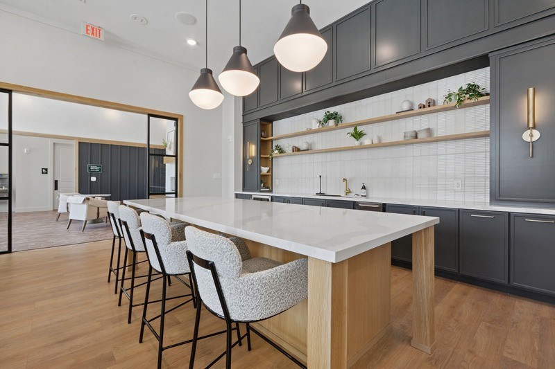 A kitchen with a long white island and chairs.