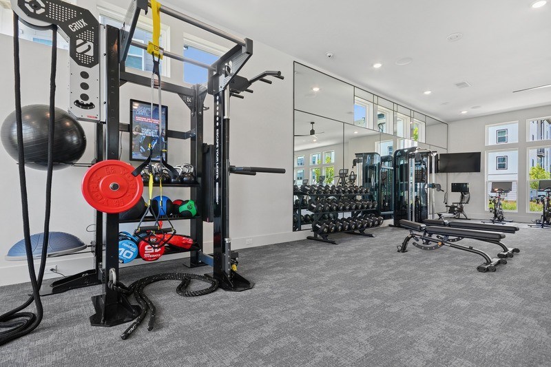 A gym with a variety of equipment including a weight machine with a red weight plate.