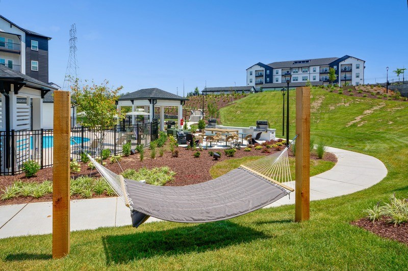 A hammock is suspended between two wooden posts in a grassy area.