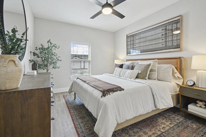 A bedroom with a large bed and a ceiling fan.
